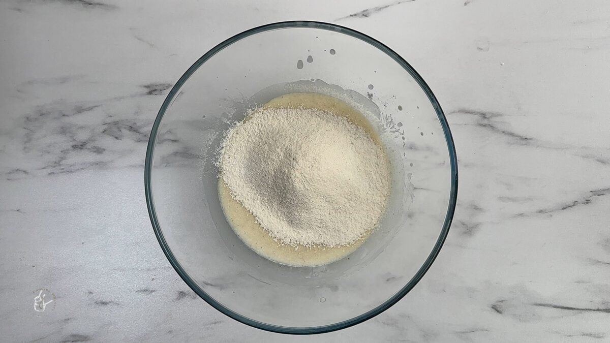 sifted flour added to the wet ingredients of the cake in a bowl