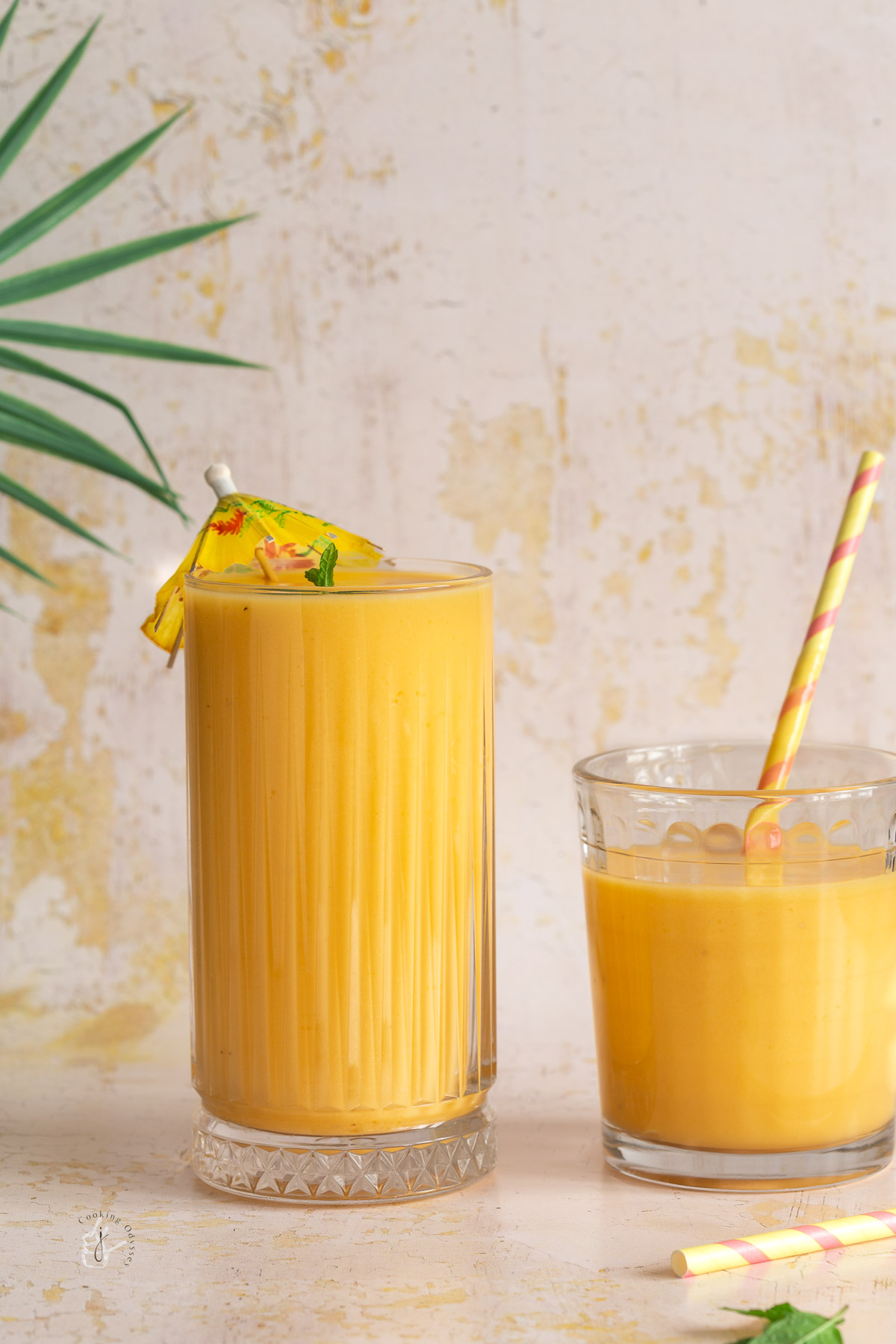 two clear glasses filled with yellow-orange coloured smoothie
