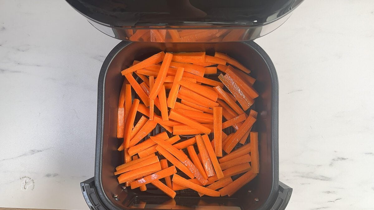 seasoned raw carrot sticks in the air fryer basket