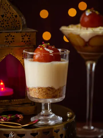 A small jar of gulab jamun cheesecake no bake placed on a round brass tray