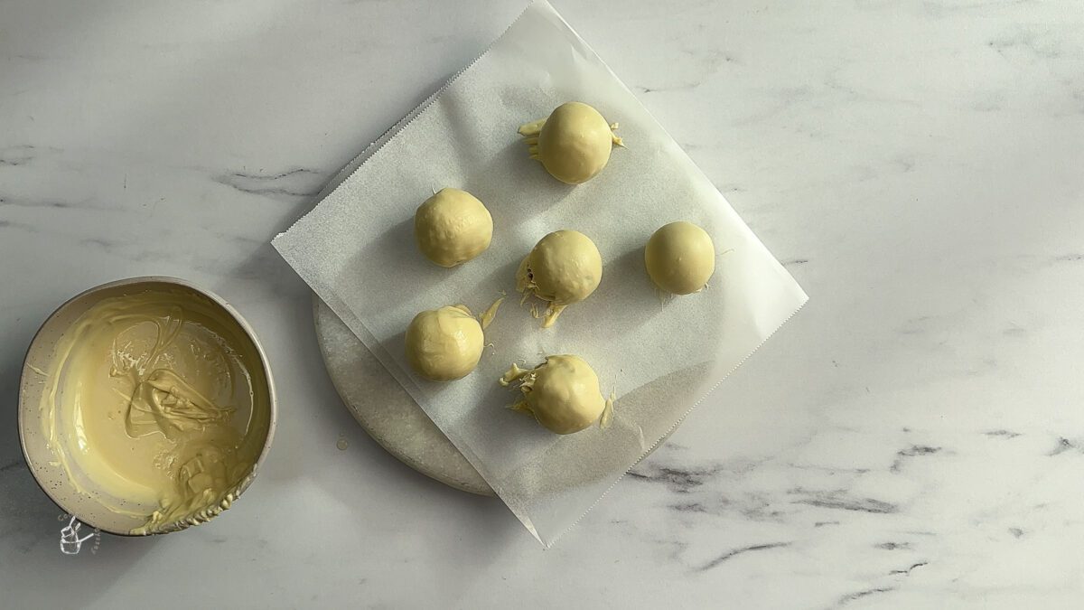 white chocolate coated gulab jamun placed on a parchment paper to set