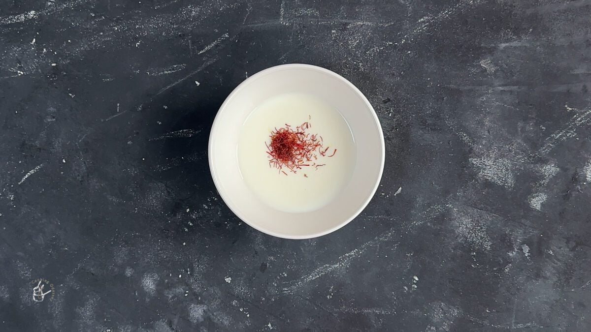 saffron strands added to the warm almond milk in small bowl