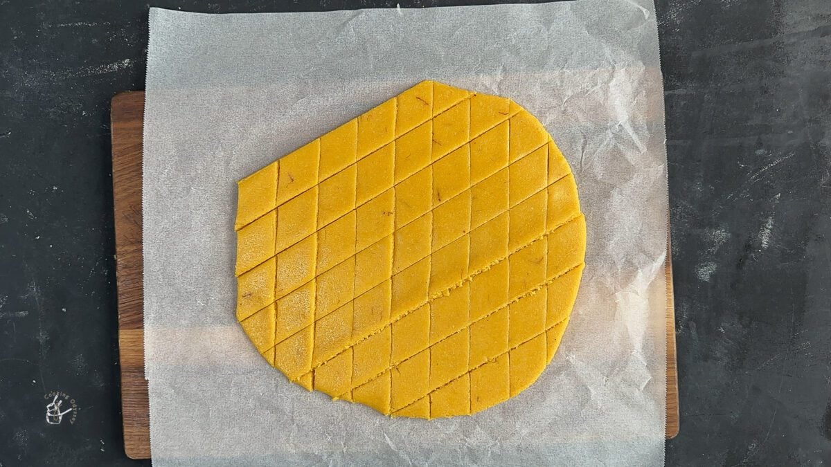 kesar katli dough rolled and cut into diamond shape on the greasproof paper