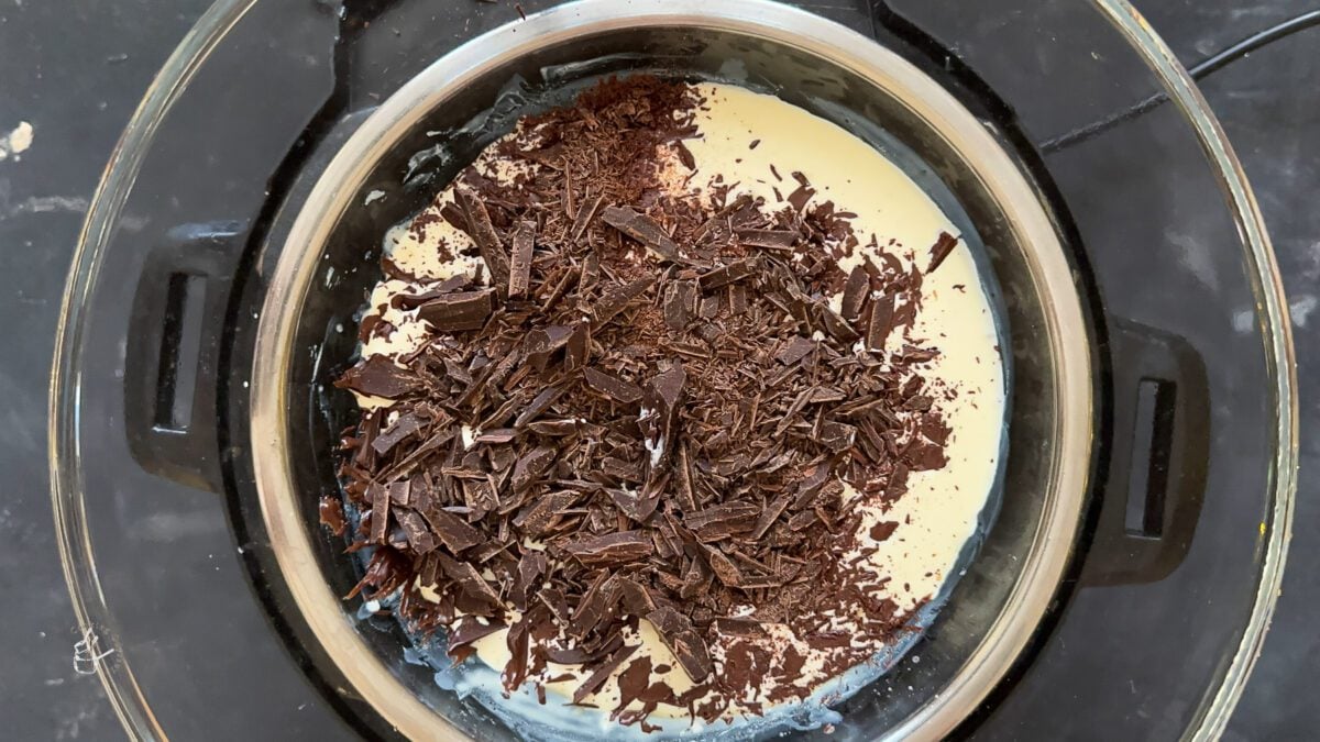 chopped chocolate tossed in warm cream in a bowl to make christmas chocolate truffles.