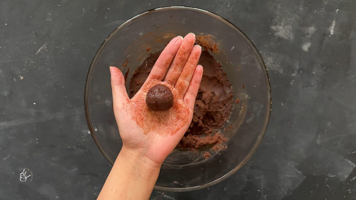 A female hand is showing a truffle in her hand. 