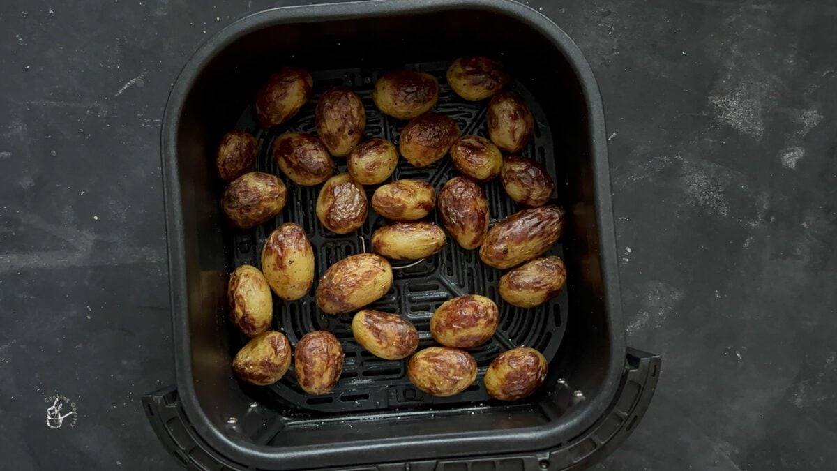 baked mini potatoes are in the air fryer basket.
