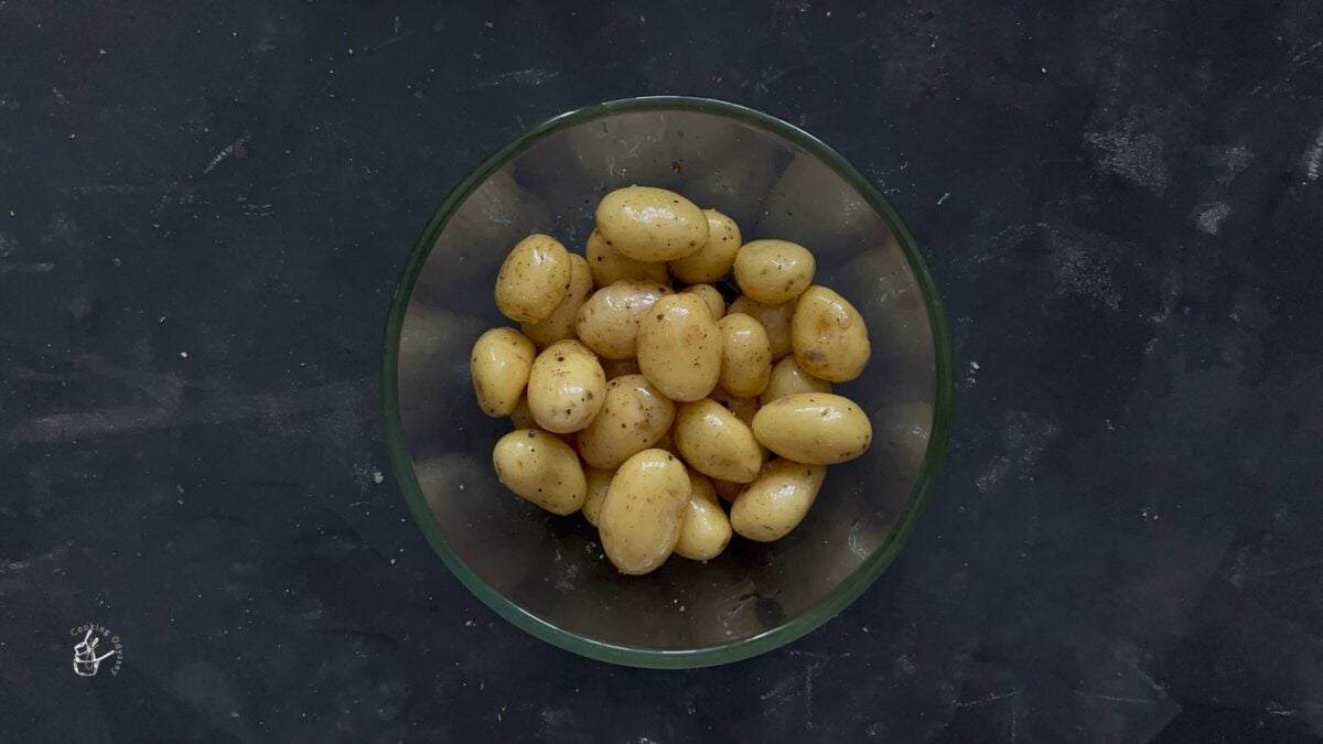 seasoned mini potatoes coated in oil in a clear bowl.