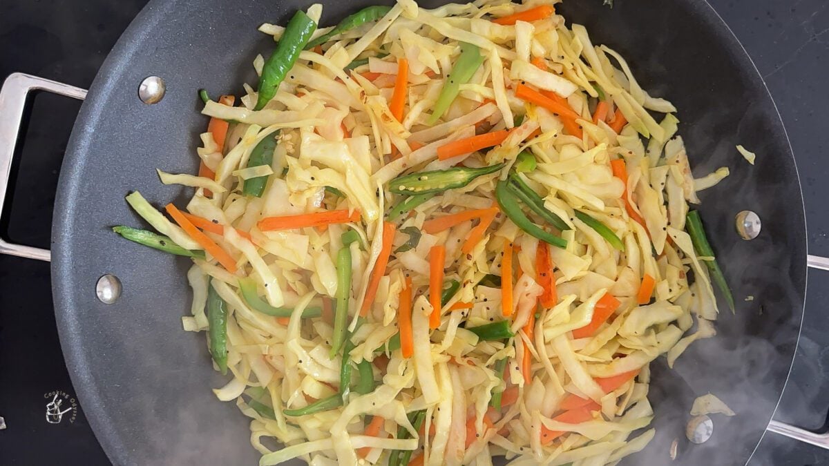 vegetables such as cabbage and carrots cooking in a wok to make cabbage sambharo.