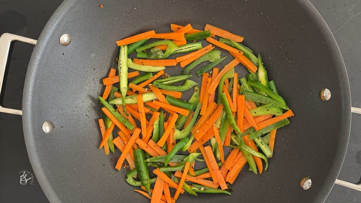 vegetables such as carrots and bell peppers added to the hot oil in a pan to make sambharo.