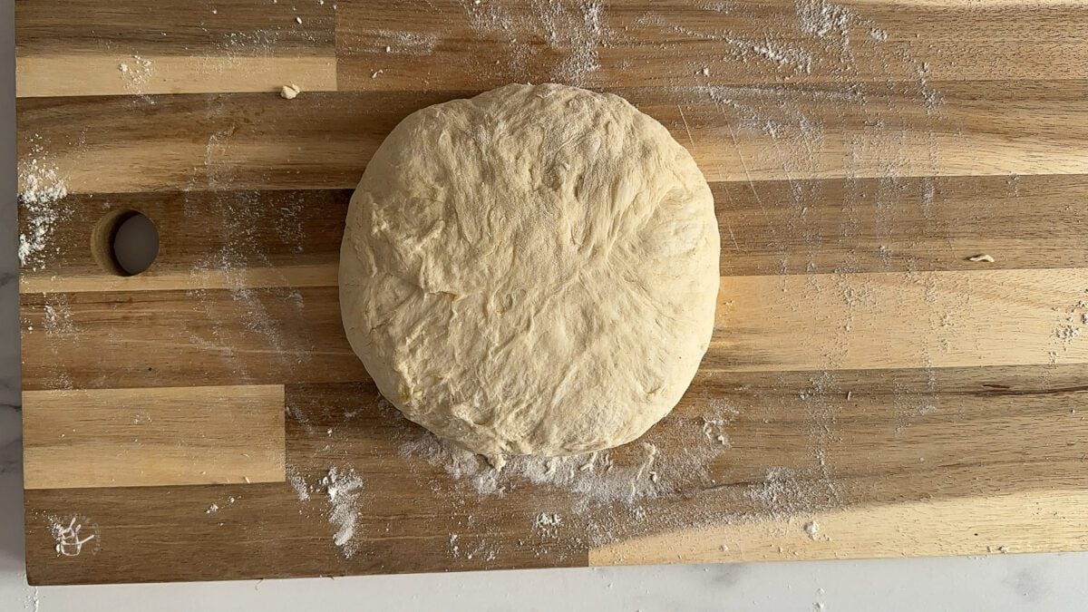 bread dough is on the wooden board.