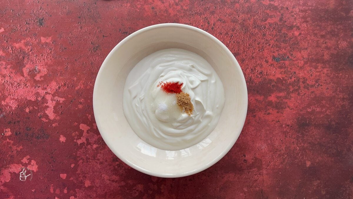 In a bowl yogurt and spices are added to make mixed fruit raita.