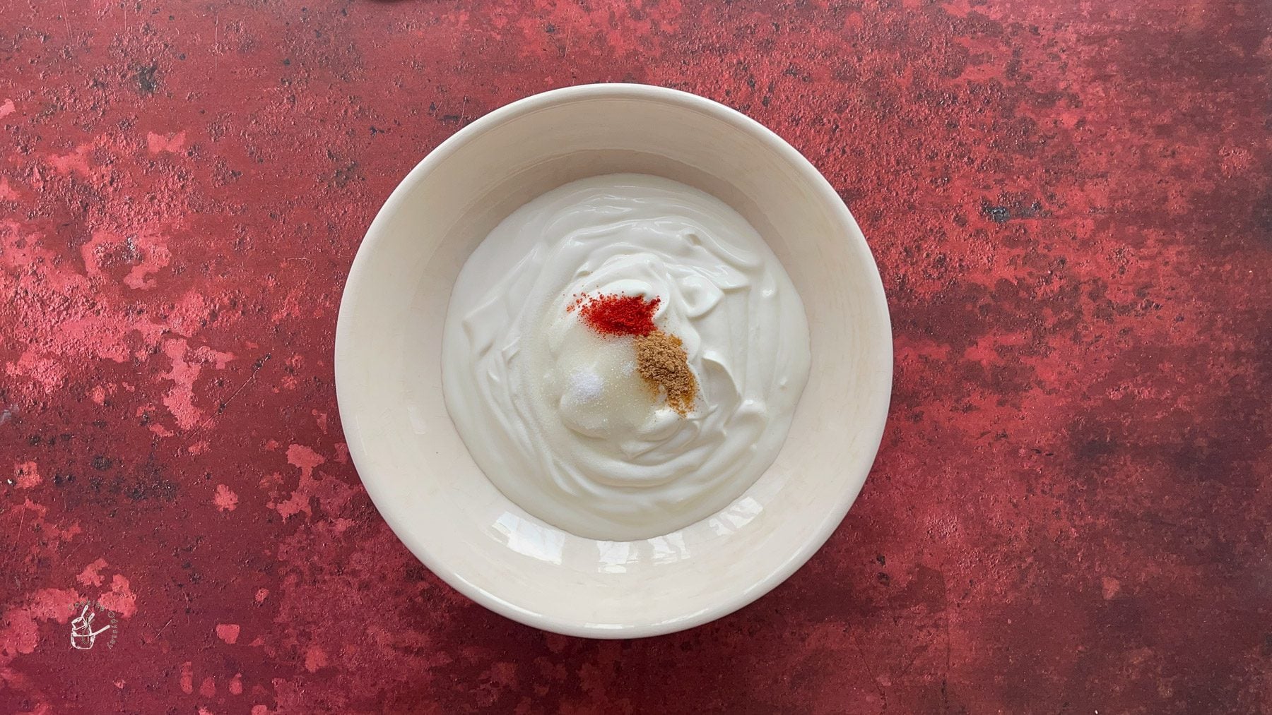 In a bowl yogurt and spices are added to make mixed fruit raita.