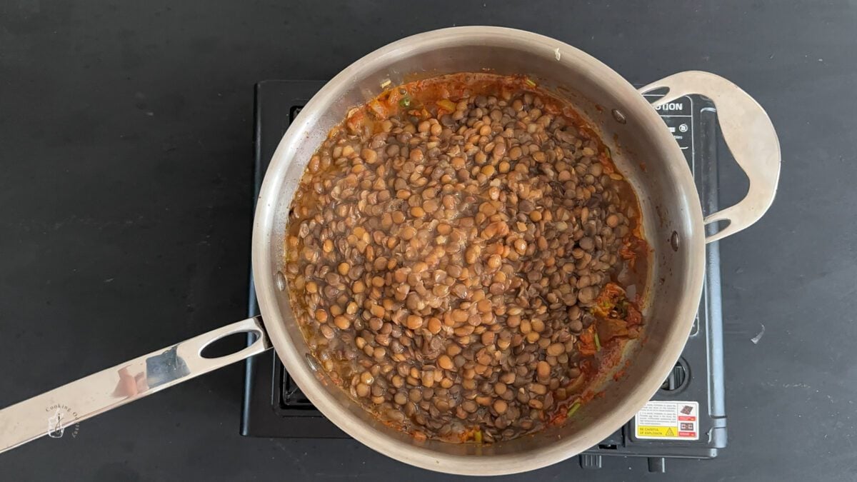 boiled green lentils added to the onion tomato curry base mixture in the pan.