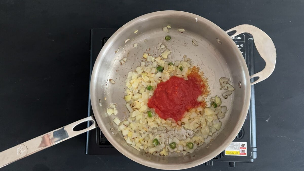 crushed tomatoes added to the onion mixture in the pan over the stovetop.
