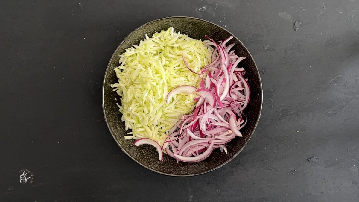grated raw mango and onion slices in a black mixing bowl.