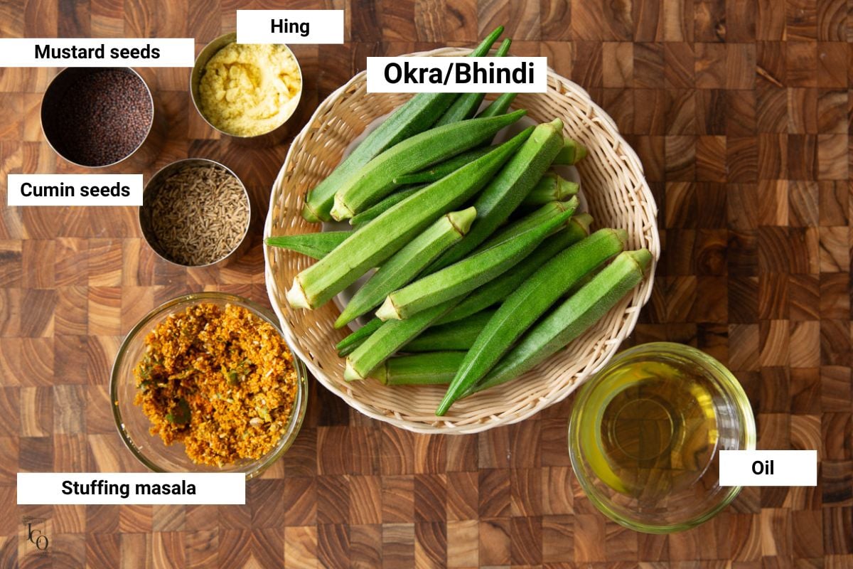 Fresh okra, oil and spices in small bowls.
