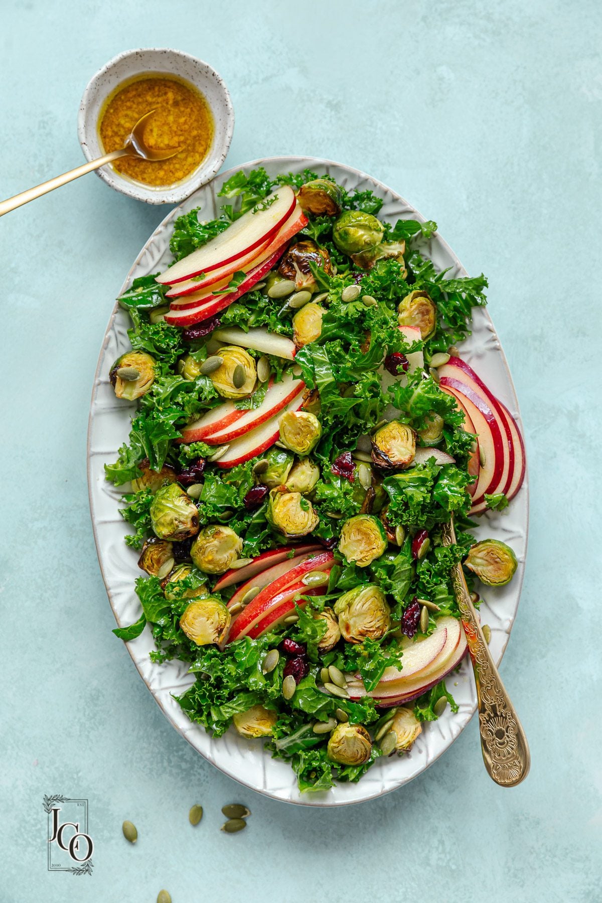 brussels sprouts and kale salad served in a serving platter with serving spoons.