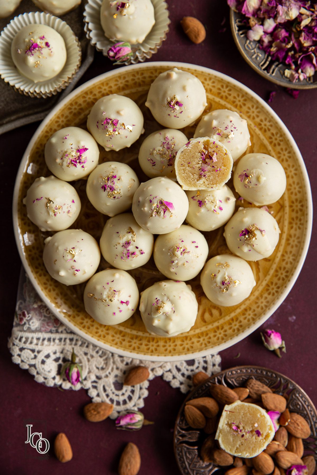 Badam halwa truffles coated in white chocolate, arranged on a yellow serving plate.