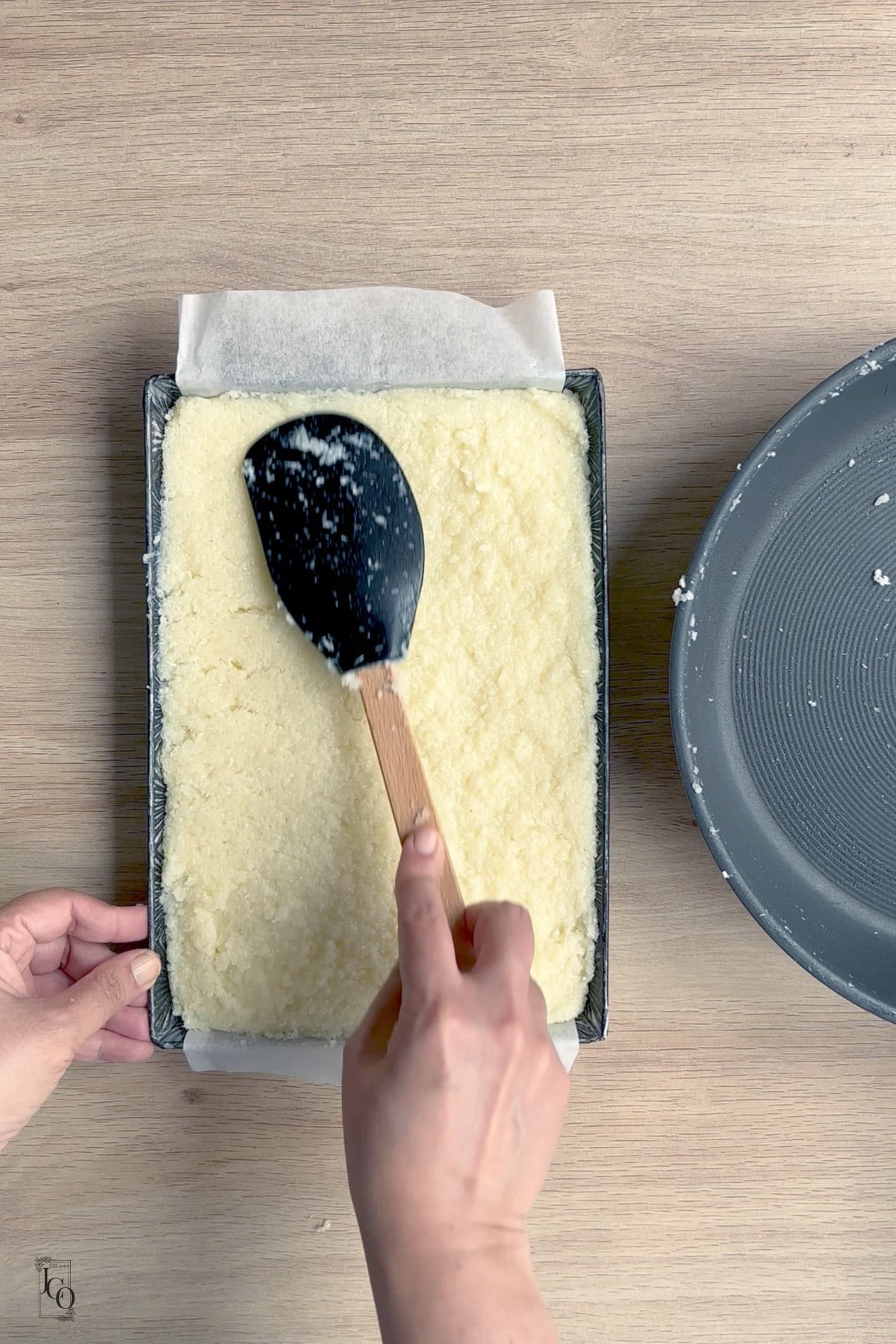 Coconut barfi mixture evenly spread in a lined tray. 