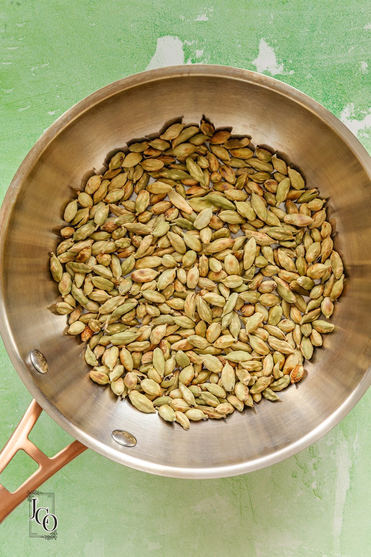 Lightly toasted green cardamom pods in a pan.