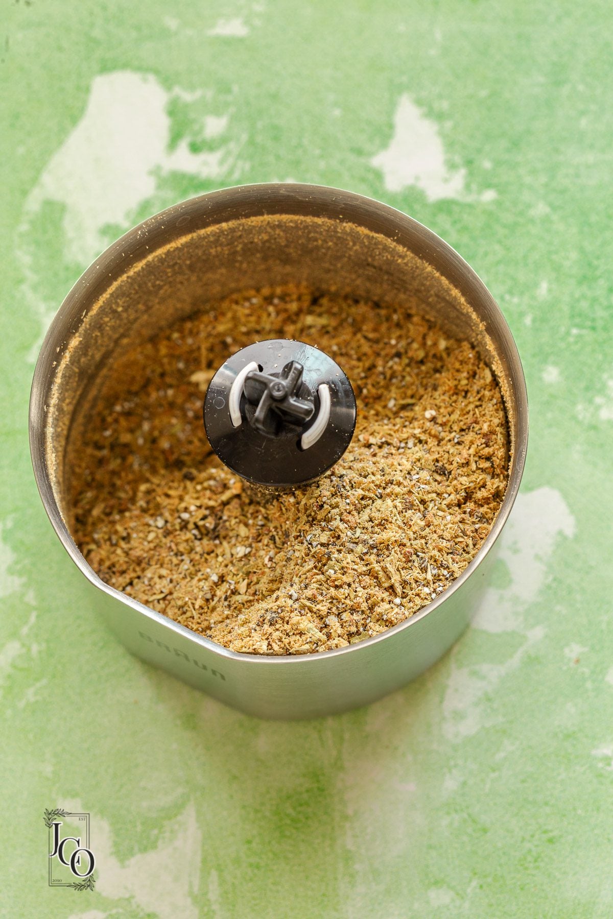 Ground toasted cardamom in a spice grinder jar.