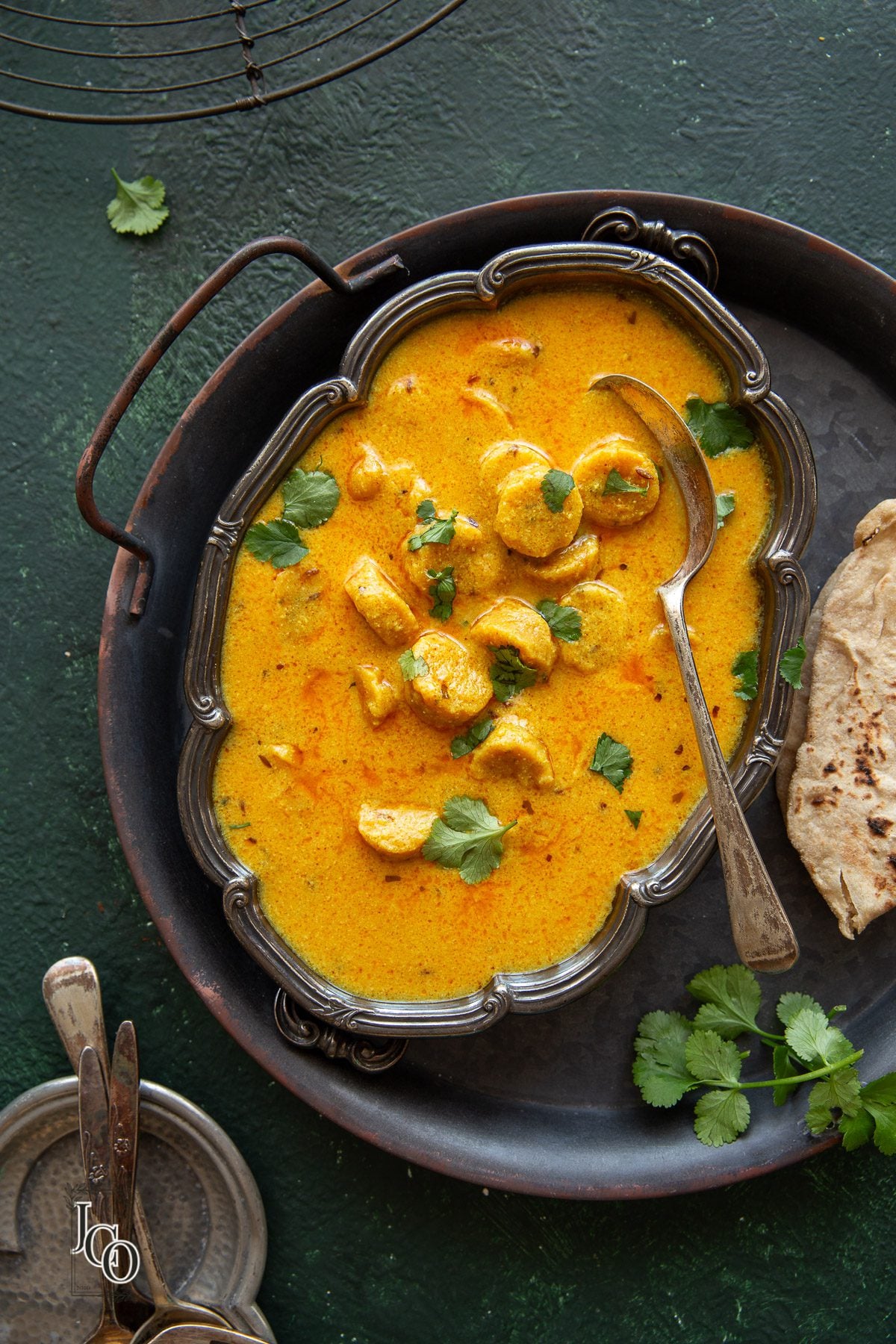 Gatte ki sabji bowl placed on a metal serving tray.