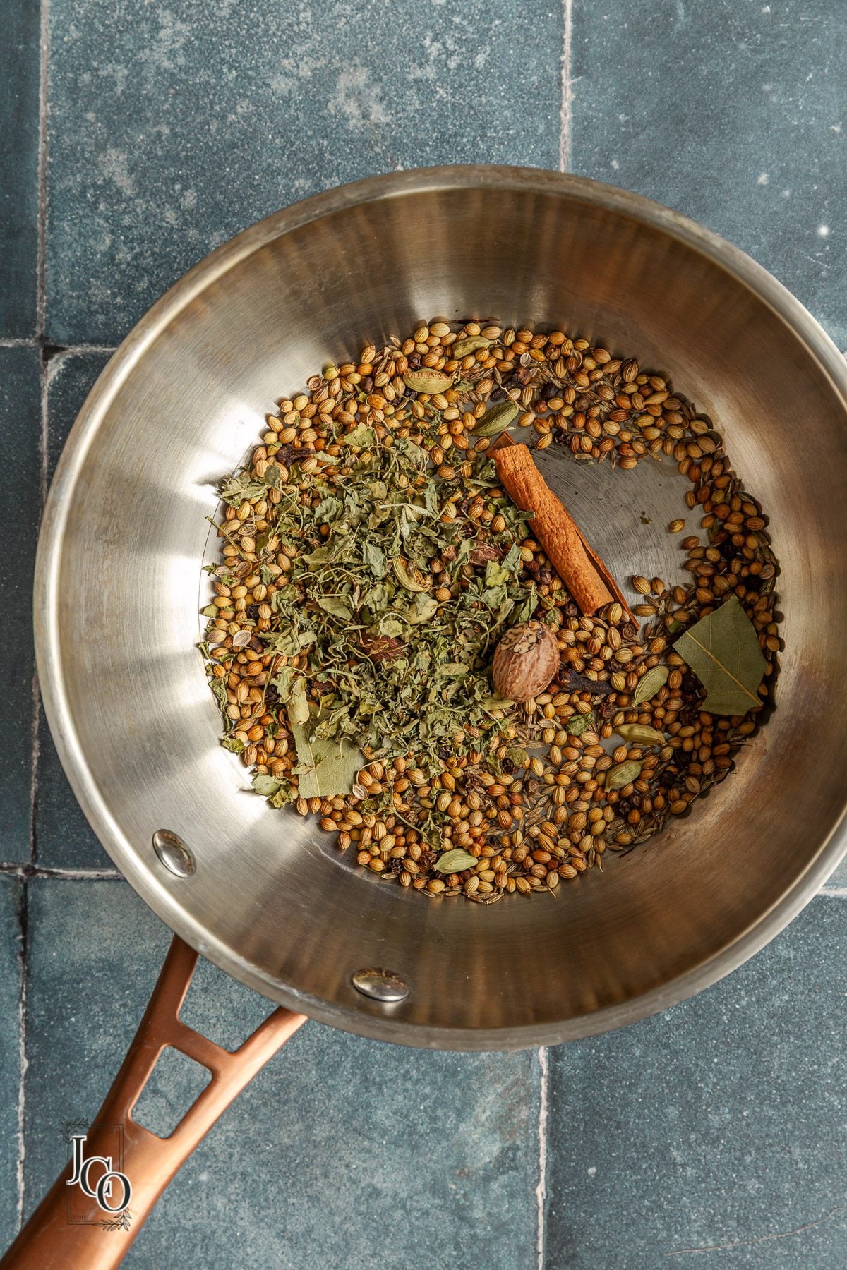 Nutmeg and kasoori methi added to the toasted whole spices in a frying pan.