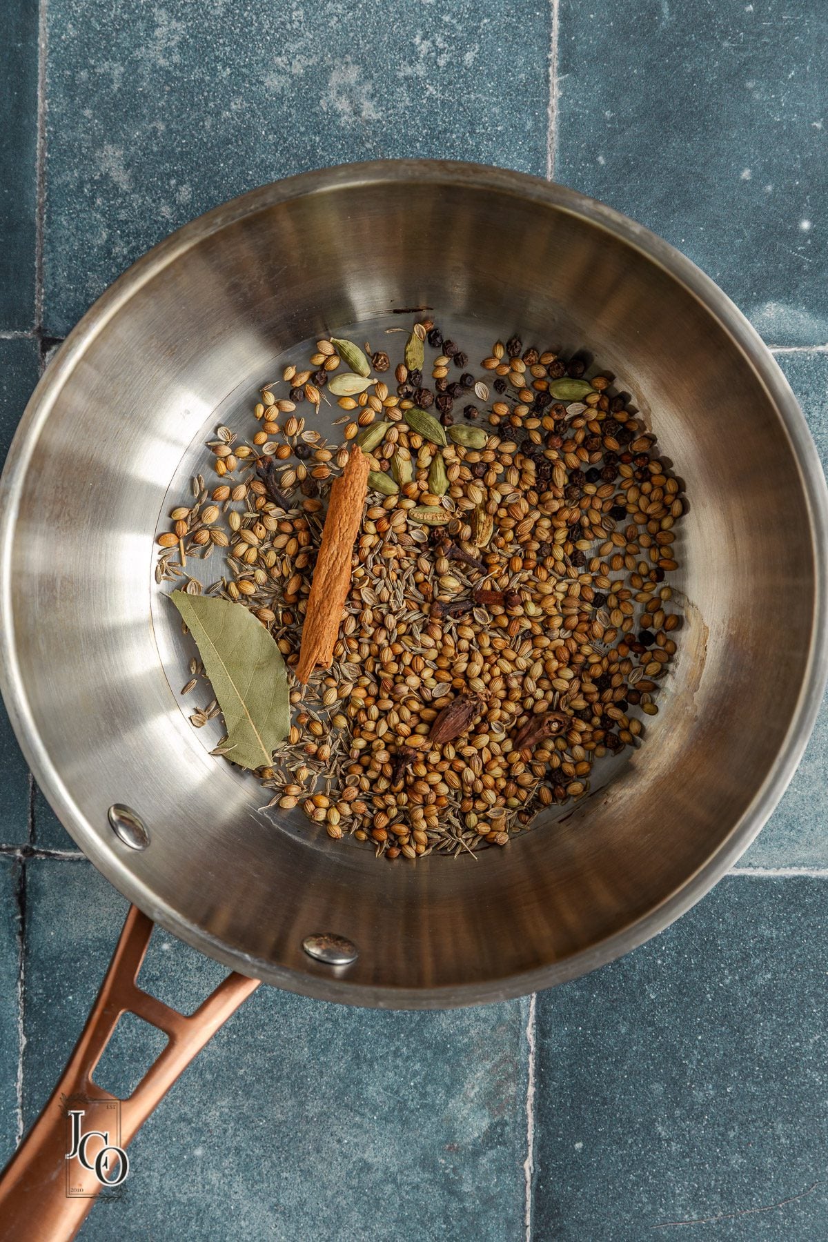 Whole spices toasted in a frying pan.