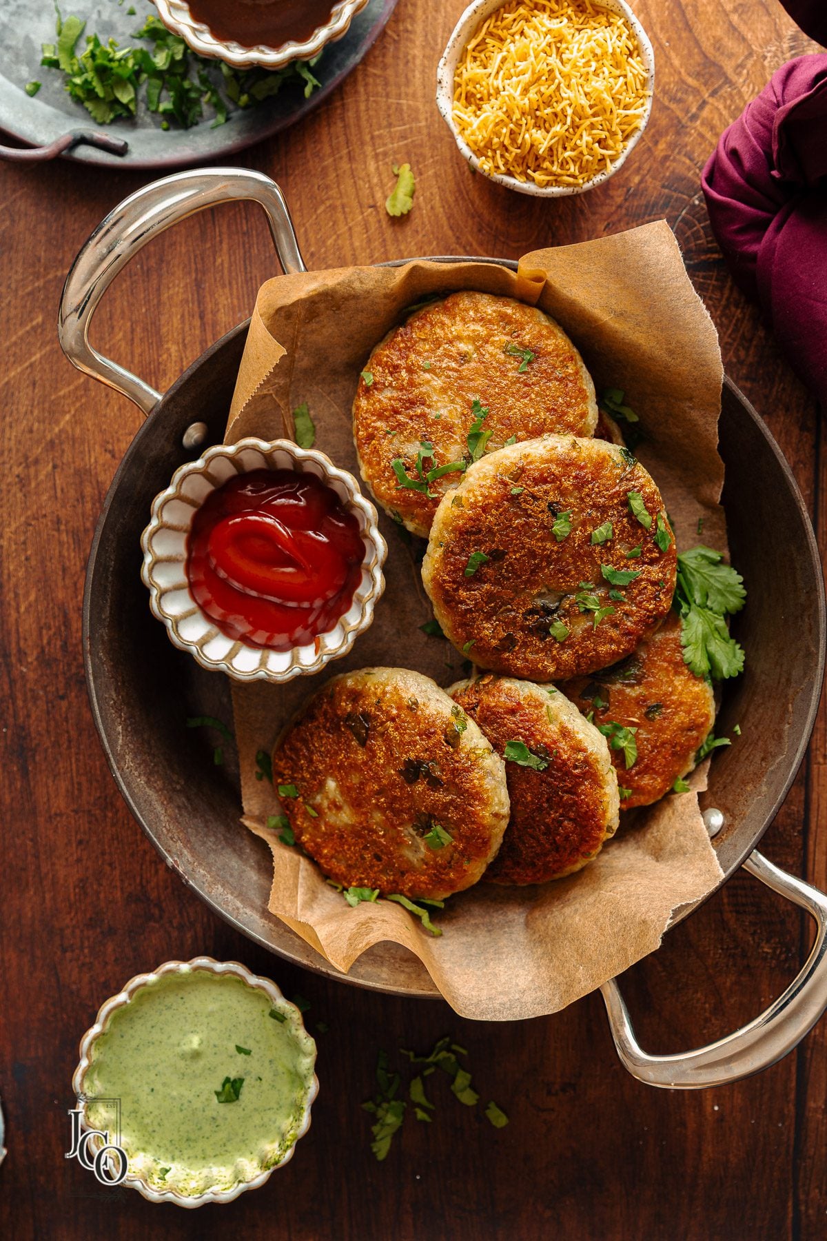 Indian Aloo Tikkis served with chutneys on the side in a serving dish.