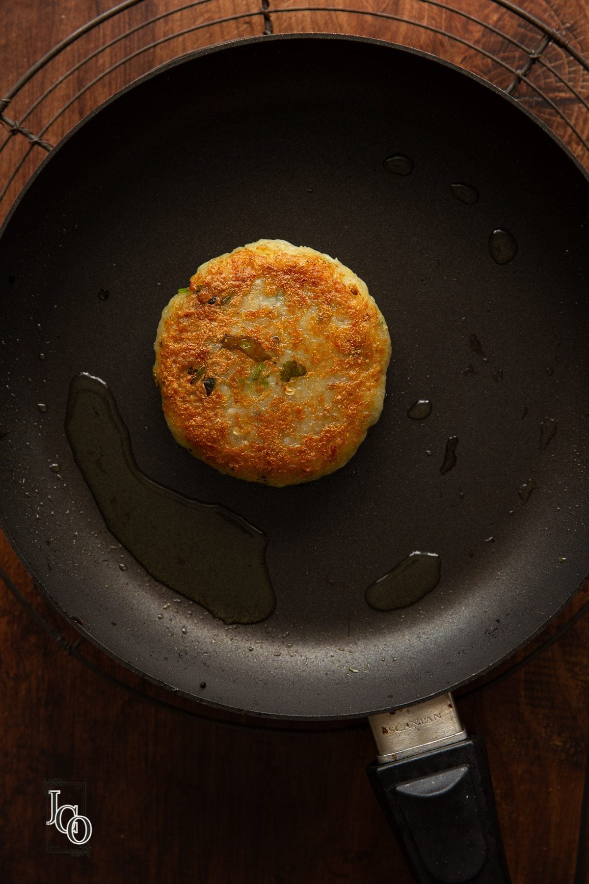 Shallow fried aloo tikki on a hot skillet on the stove.