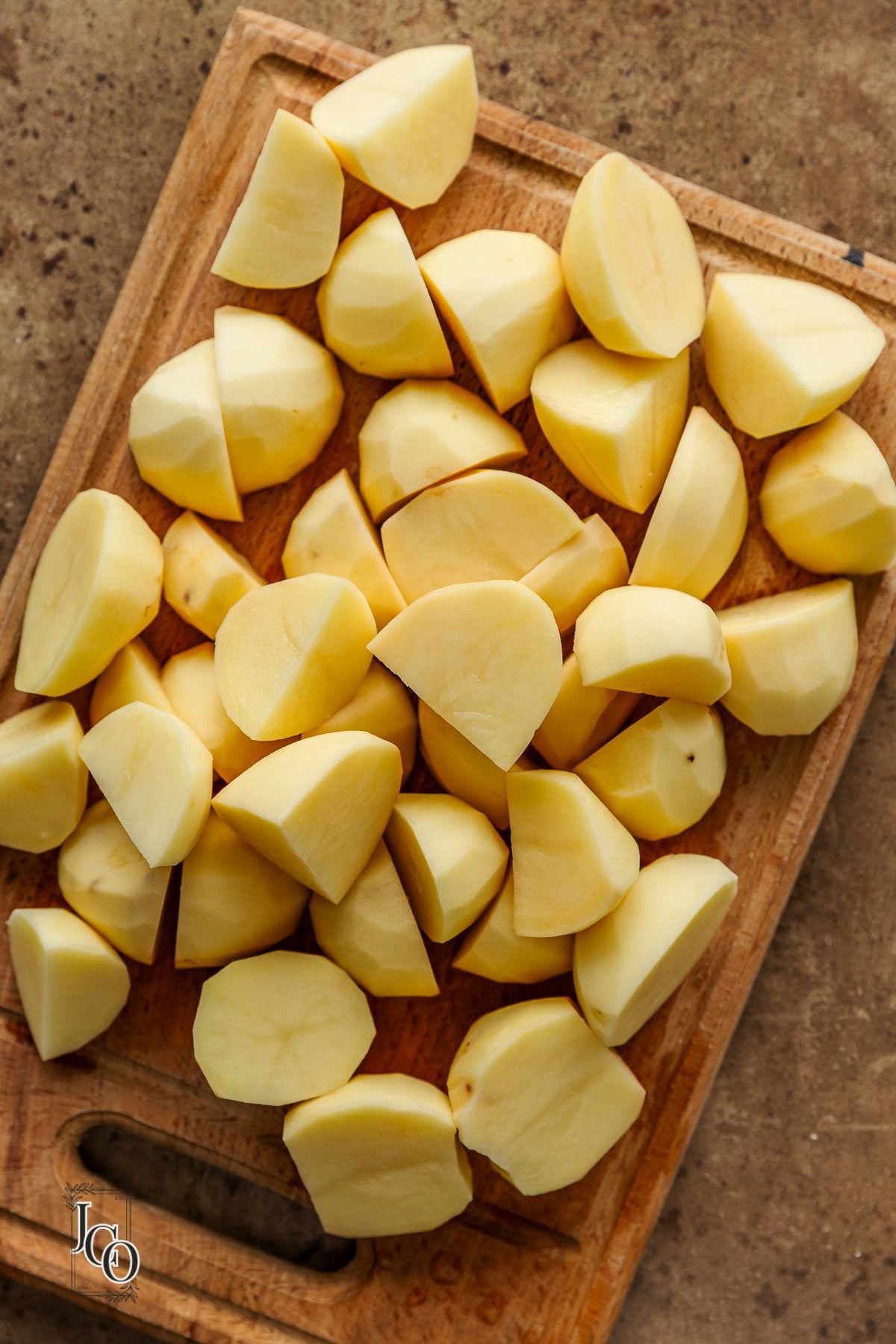 Peeled and cut raw potatoes on a chopping board.