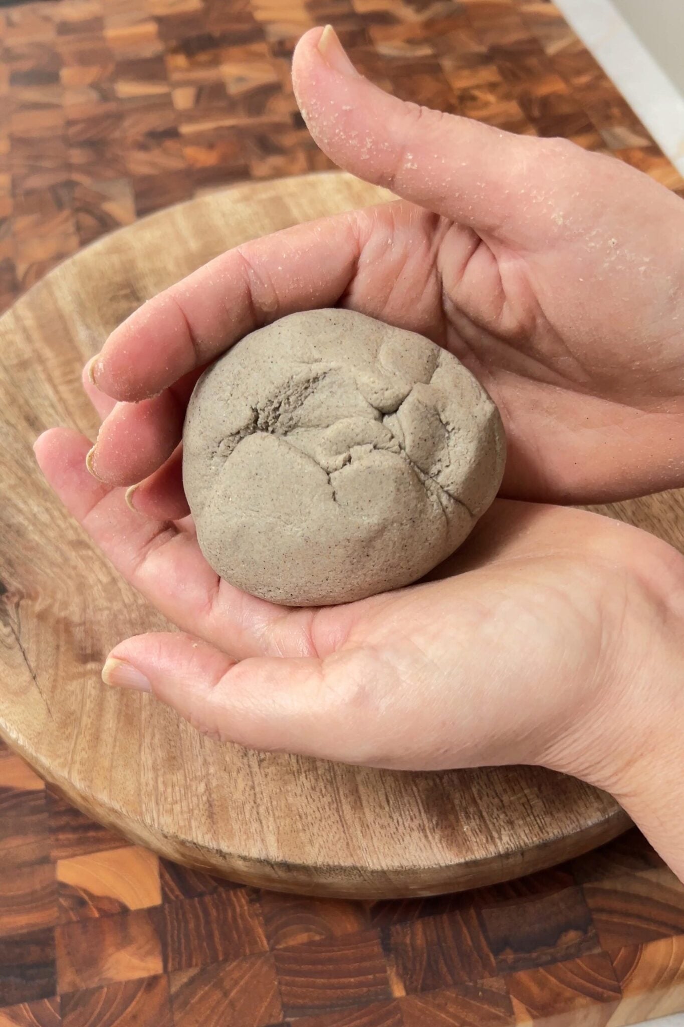 Female hand is showing sealed dough ball.