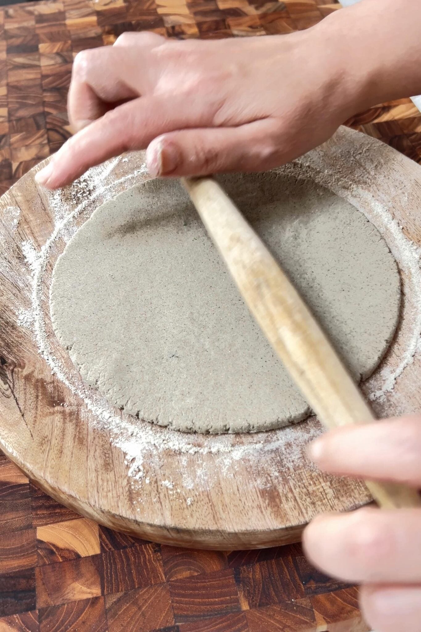 A female hands are rolling bajra rotla using a rolling pin.