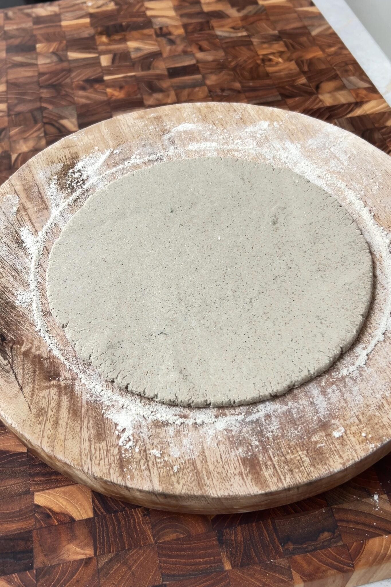 Rolled bajra rotlo without cracks on a round wooden surface.
