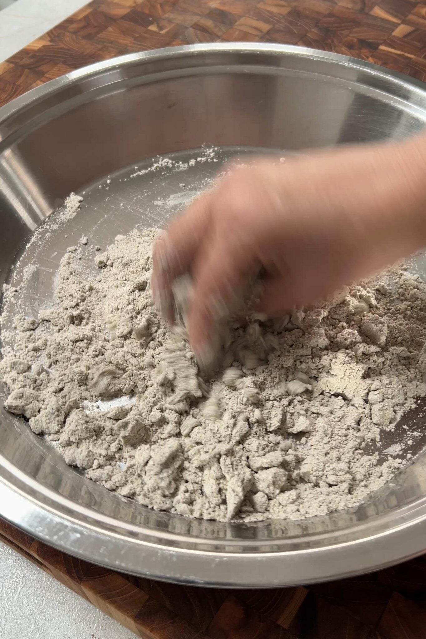 A female hand is mixing a flour with water in a plate.