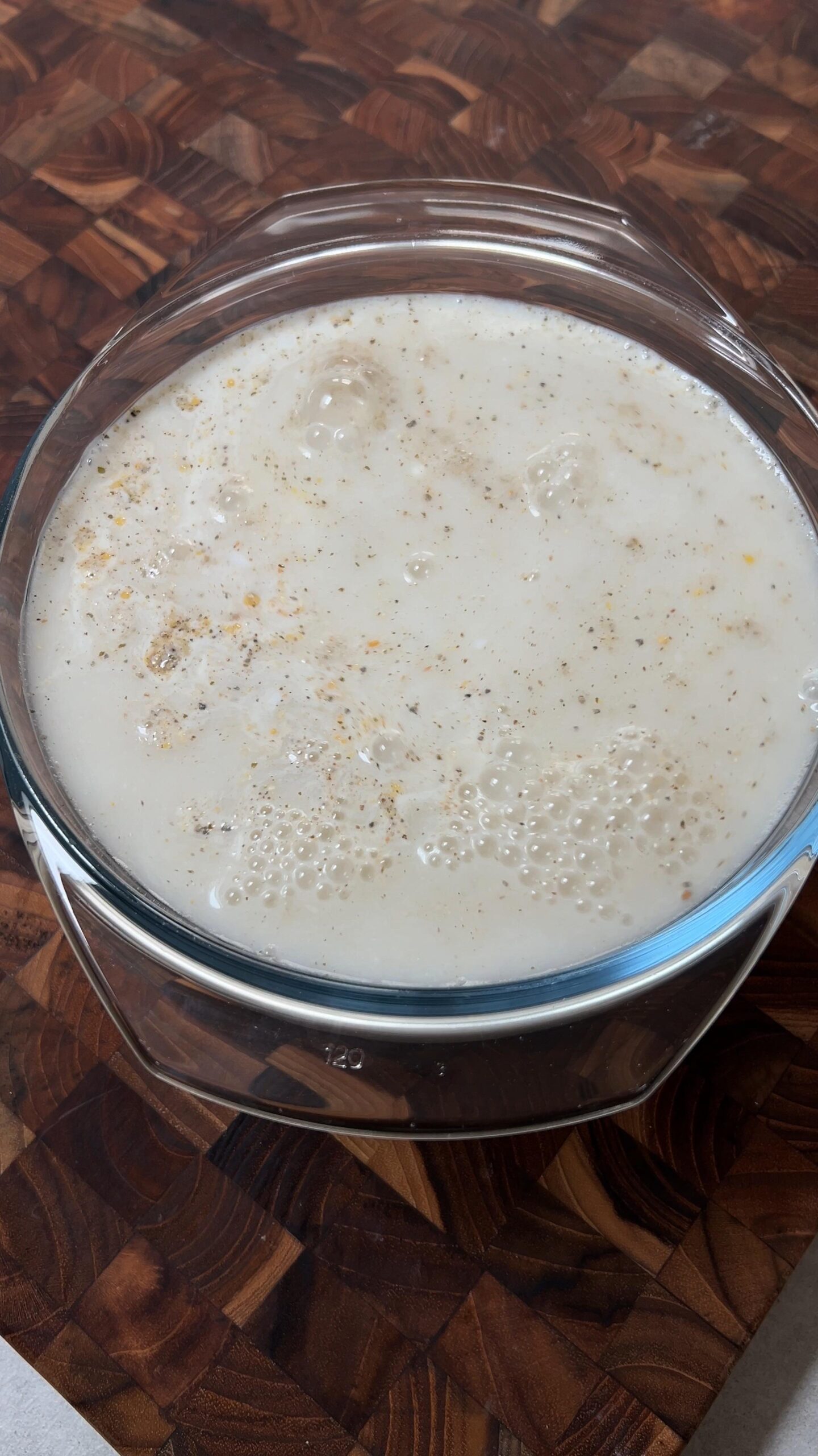 Bhaidku flour soaking in buttermilk in a clear mixing bowl on the kitchen worktop.