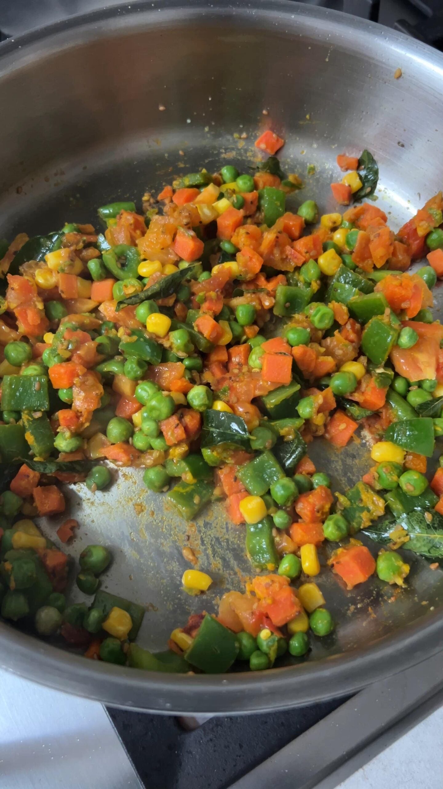 Mixed vegetables are cooking in a pan over the stovetop.