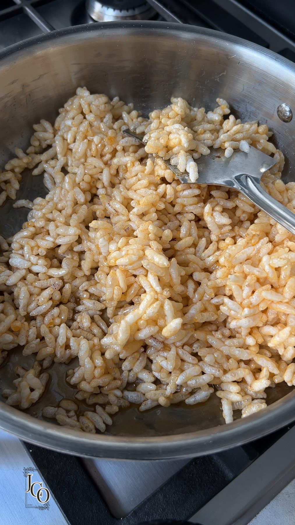 Loose hot mixture of puffed rice and jaggery in a pan.