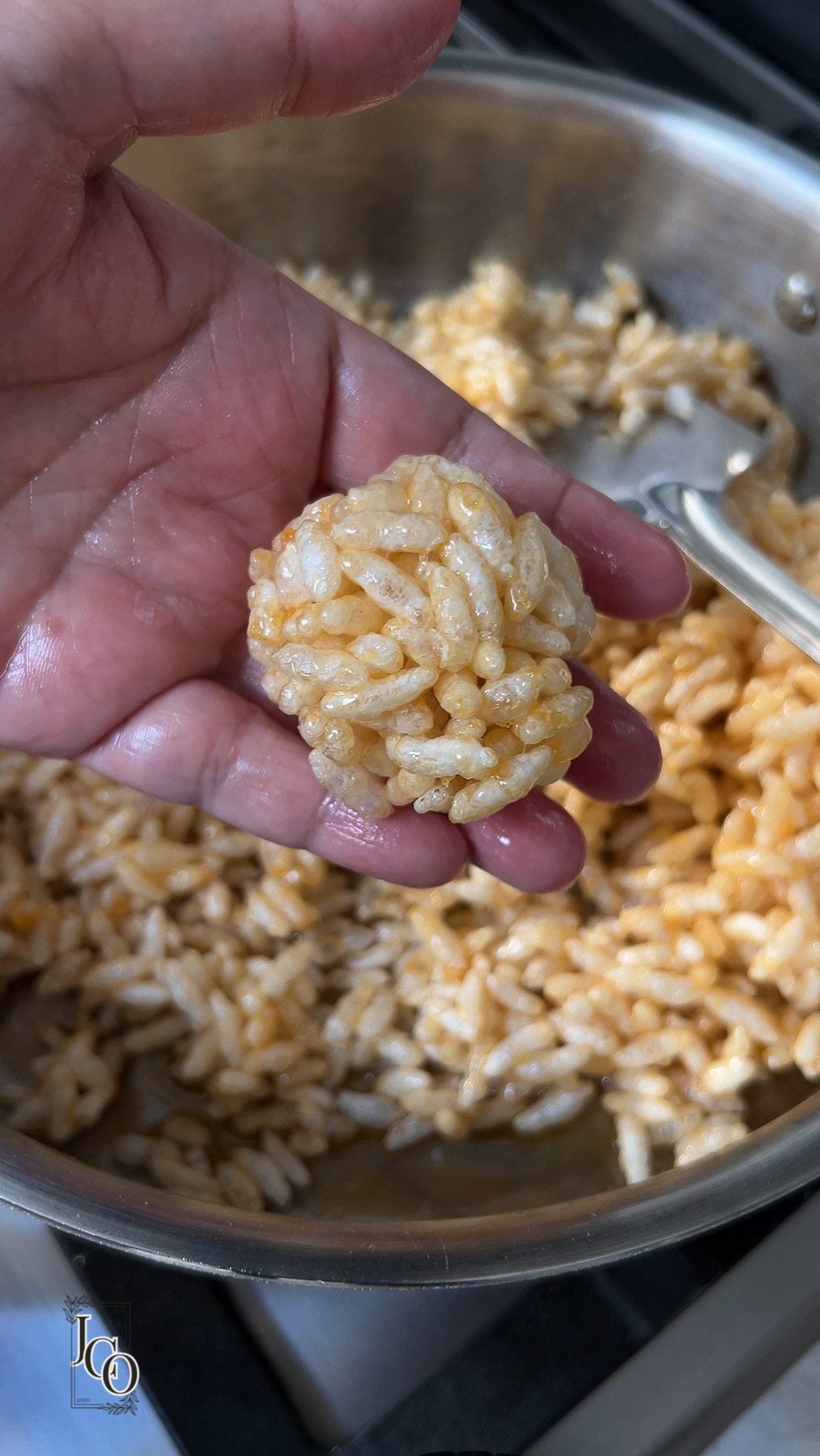 A female is holding one rolled mamra ladoo in her hand.