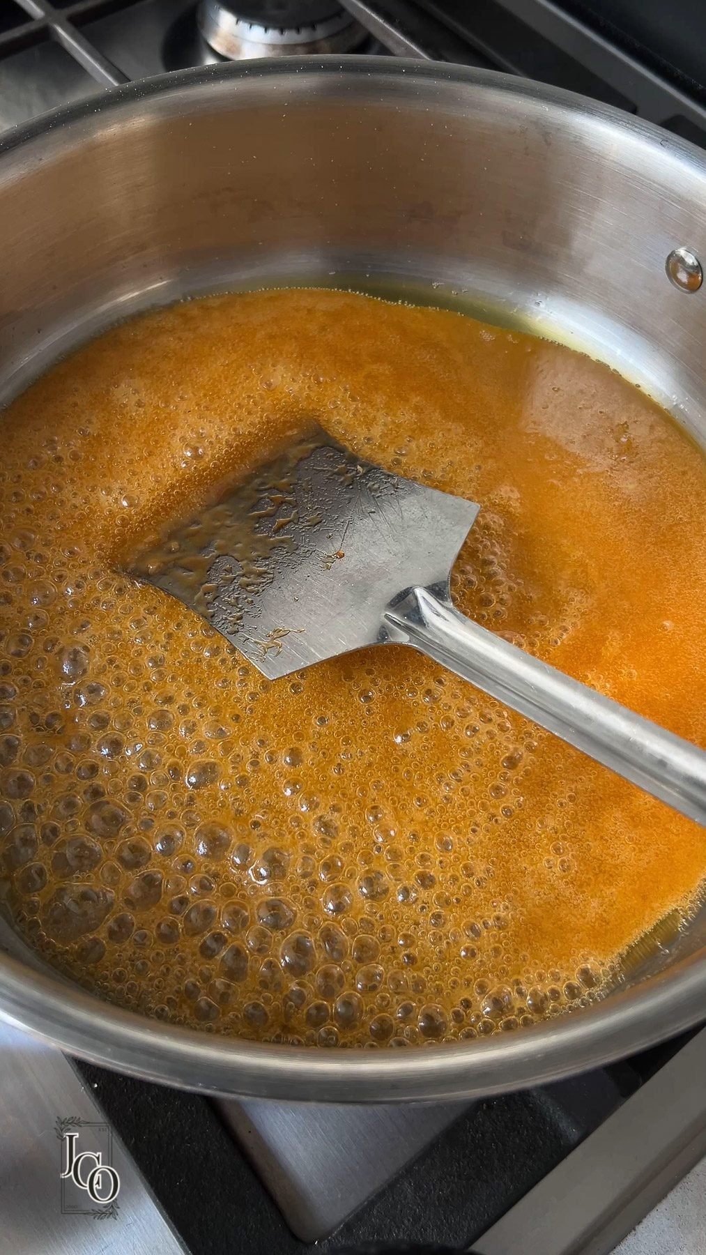 Jaggery syrup is simmering in a pan on the stovetop.