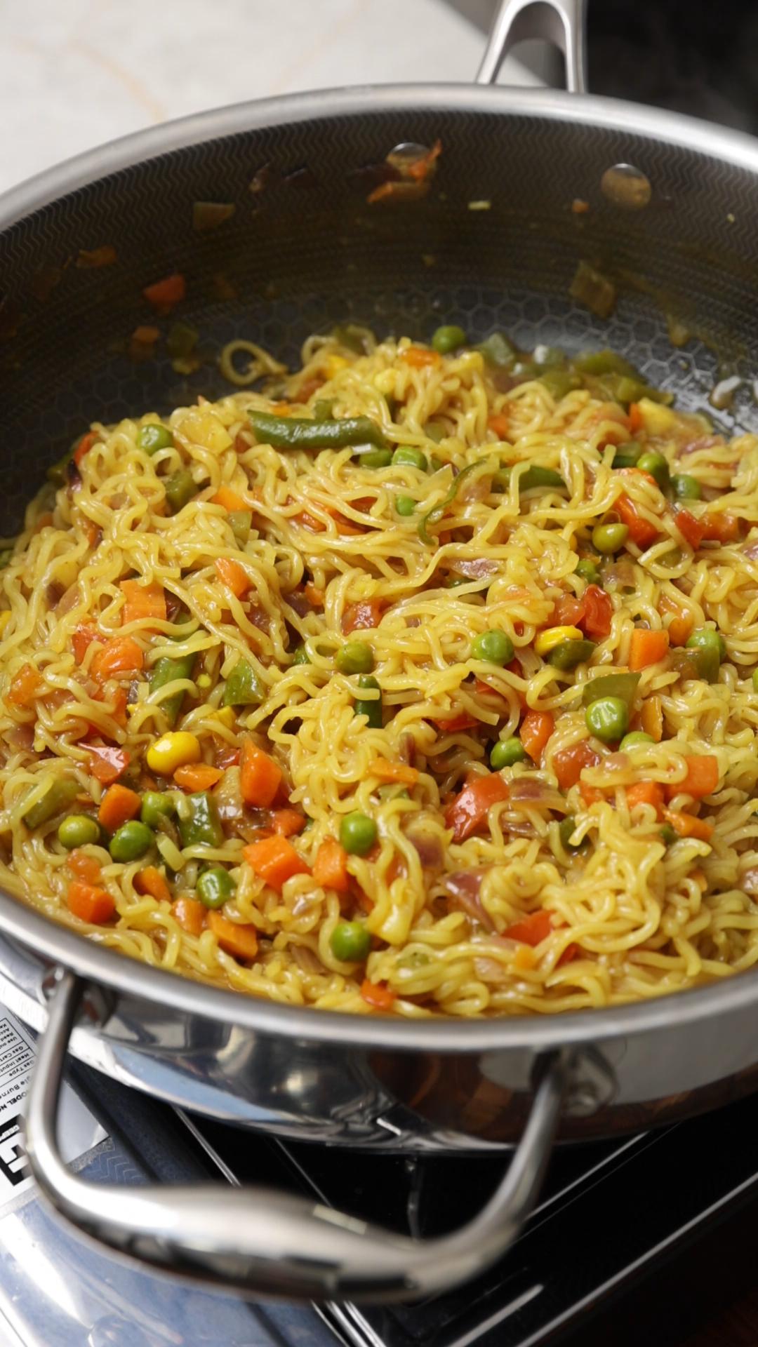 Ready to eat masala maggi noodles in a pan on the stovetop.