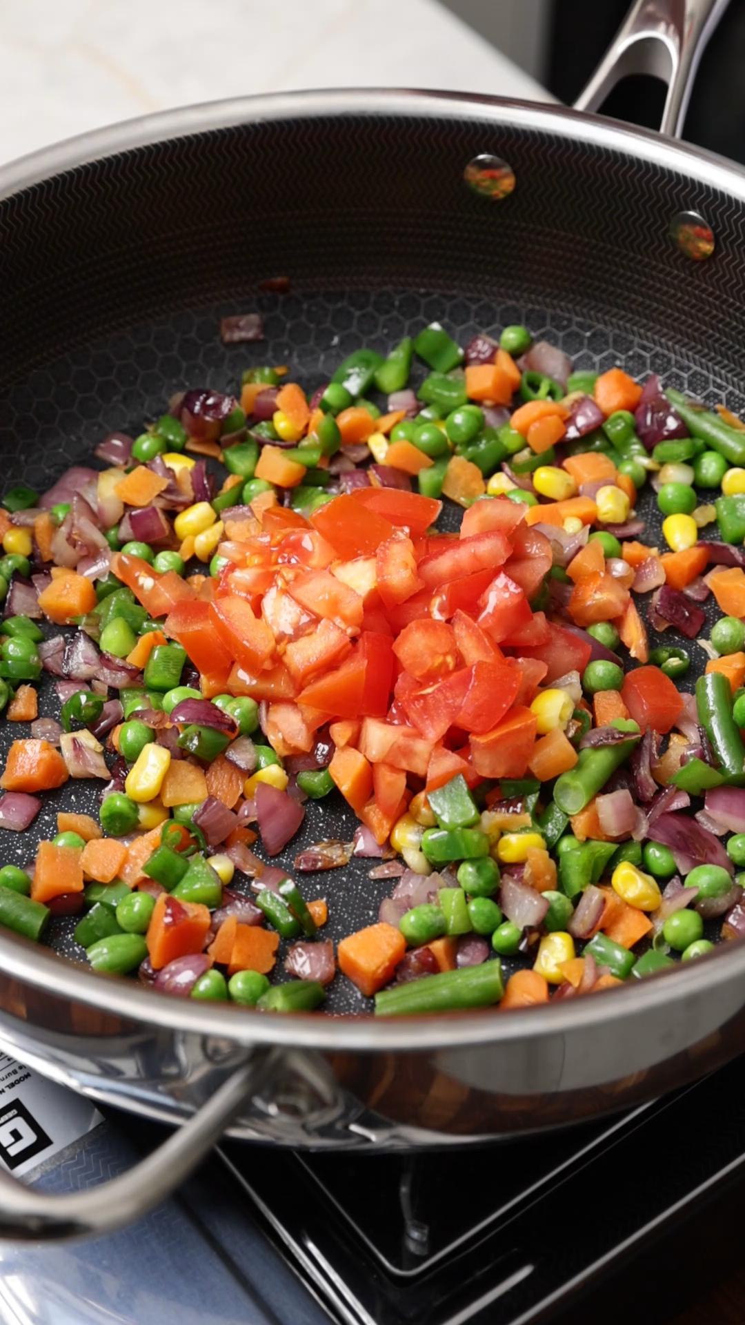 Mixed vegetables and chopped tomatoes added to the cooked onion and green peppers to make masala maggi vegetables.