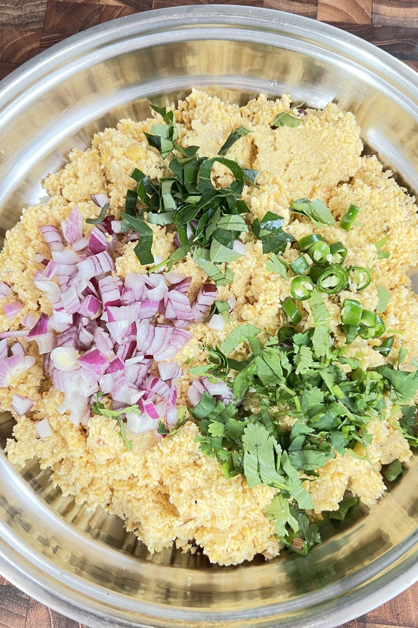 Chopped onion, curry leaves, green chillies and coriander leaves added to the chana dal paste.