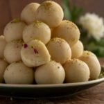 A stack of coconut almond ladoo on a plate on the wooden serving board.