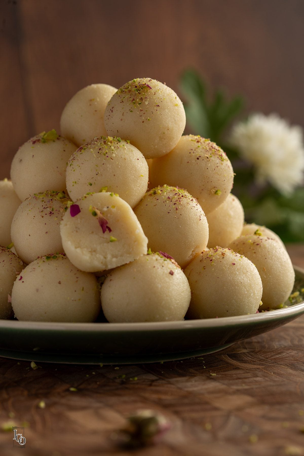 A stack of coconut almond ladoo on a plate on the wooden serving board.