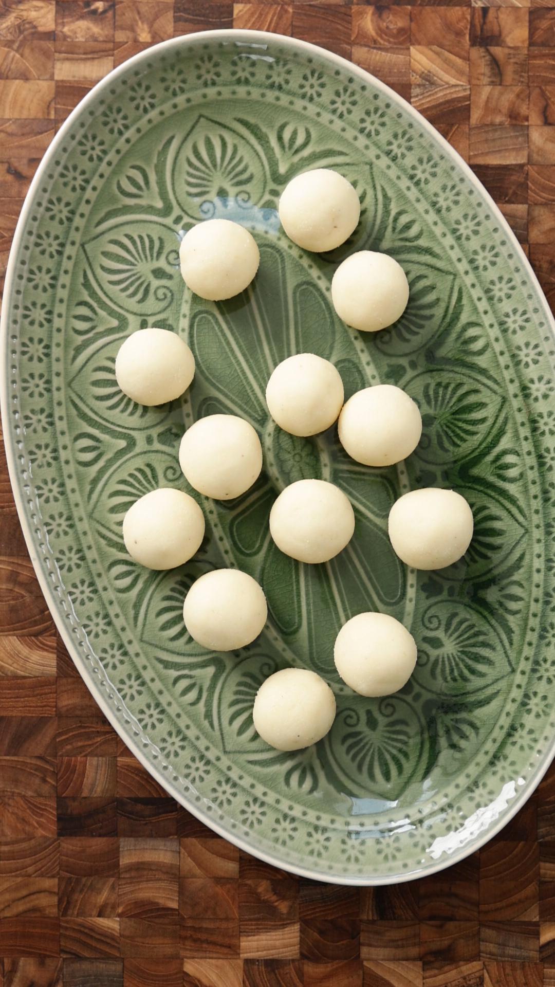 creamy coconut almond ladoo served in a green oval serving plate. 