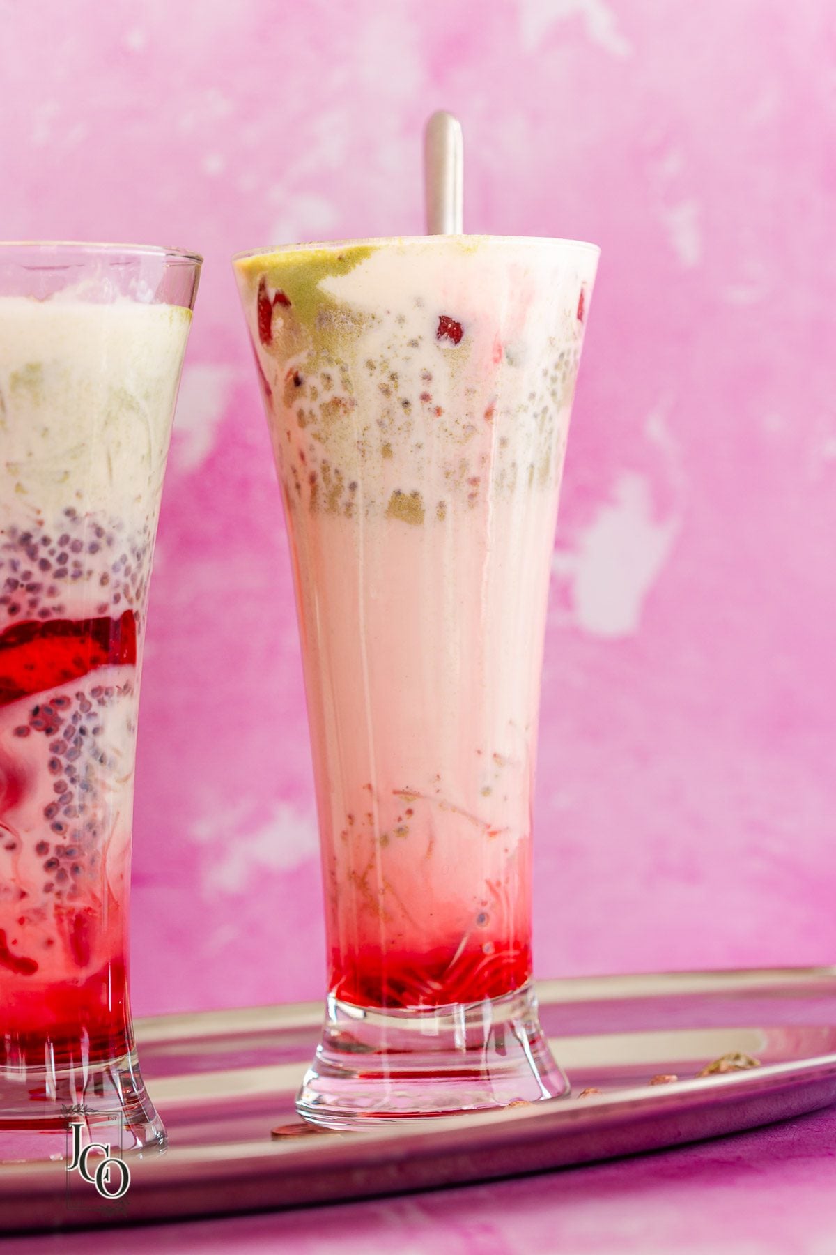 Indian summer dessert falooda served in tall clear glass and served with a dessert spoon. 