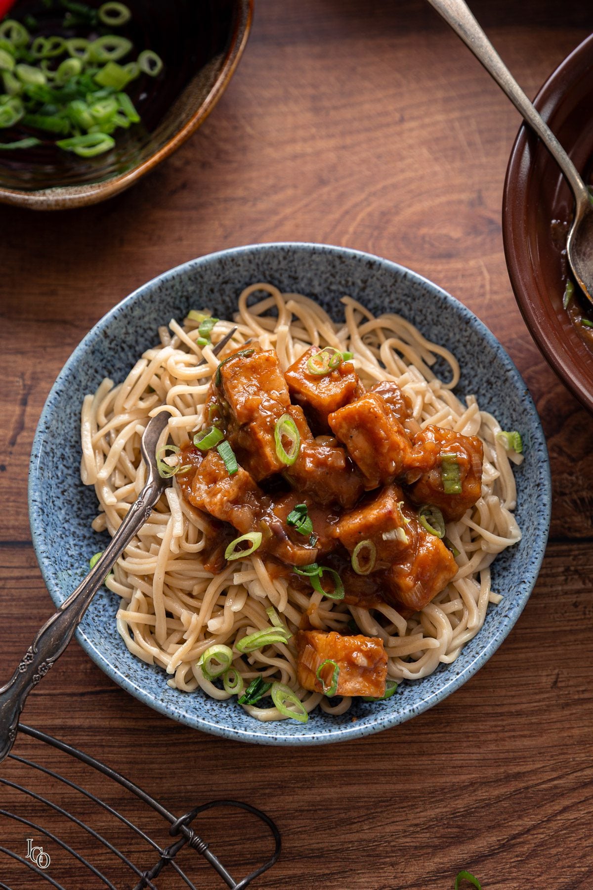 Cooked noodles served with tofu manchurian in a blue bowl.