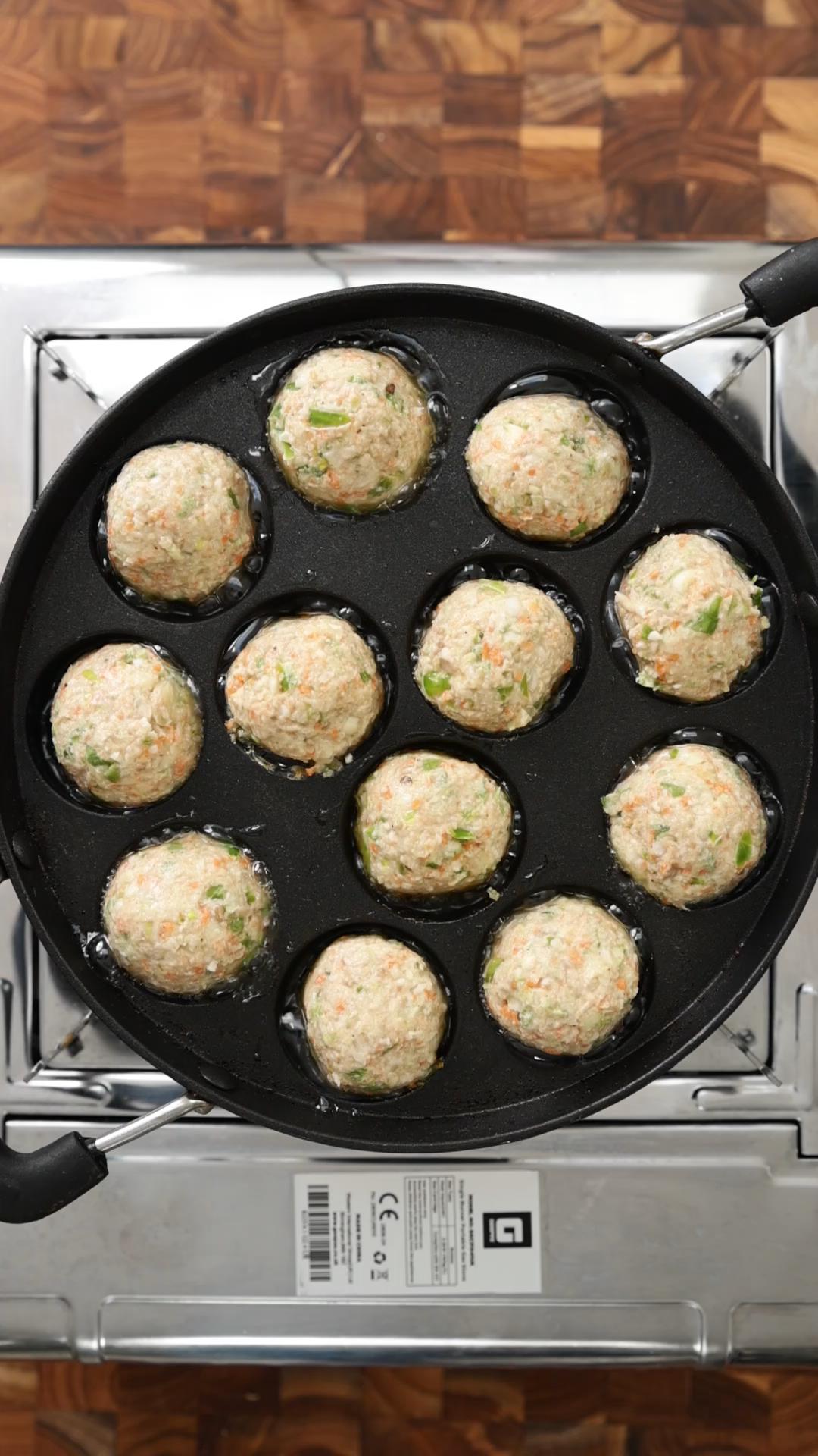 Uncooked veg manchurian balls in a paniyaram pan over the stove.