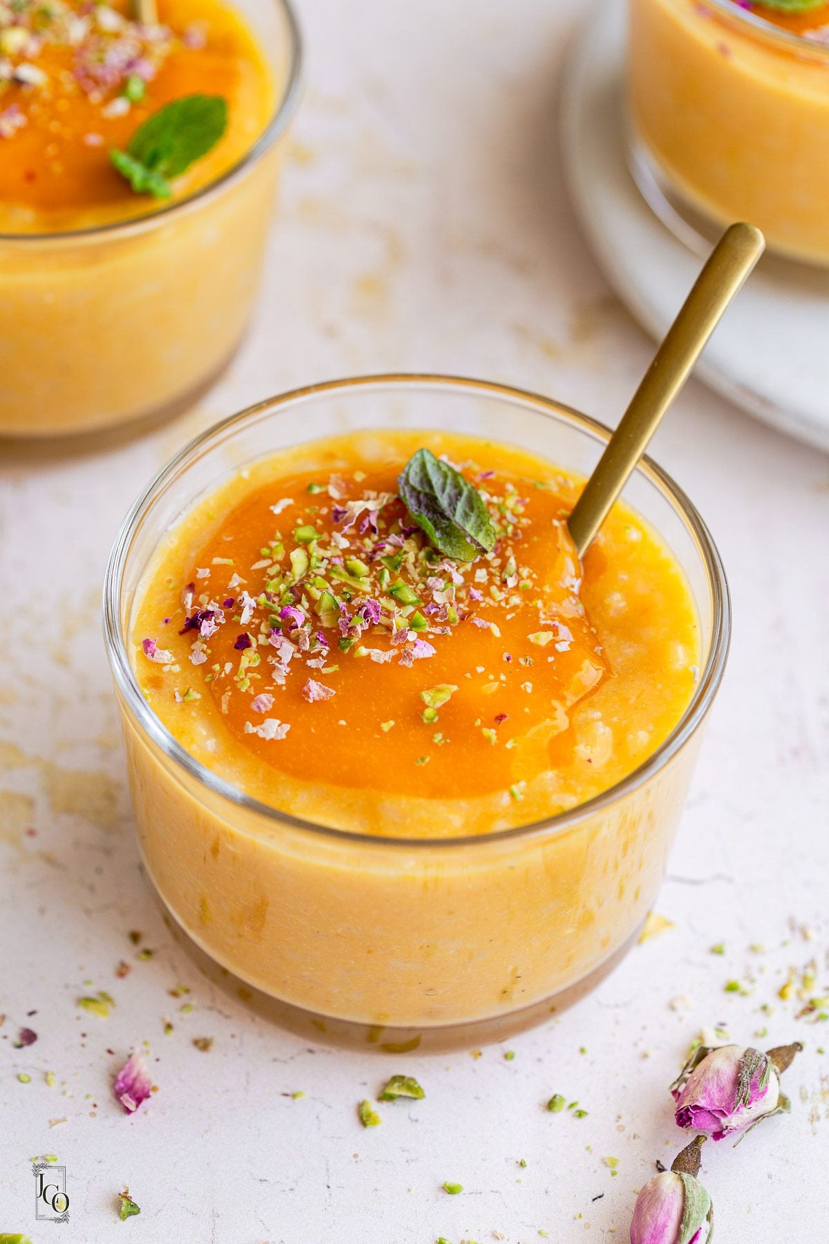 Coconut and mango doodh poha garnished with chopped nuts and rose petals.